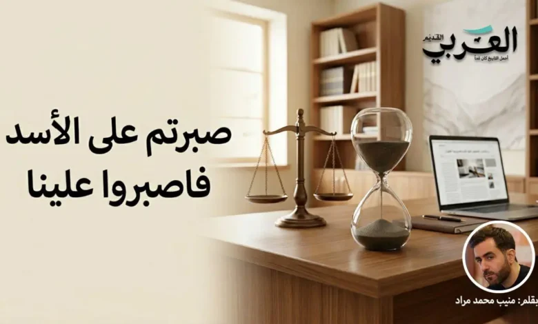 صورة تعبيرية لمكتب صحفي يضم ساعة رملية وميزان عدالة، مع صورة الكاتب منيب محمد مراد وشعار الموقع، ومكتوب عليها عبارة "صبرتم على الأسد فاصبروا علينا". تعبر عن مقالة سياسية حول المرحلة الانتقالية في سوريا.